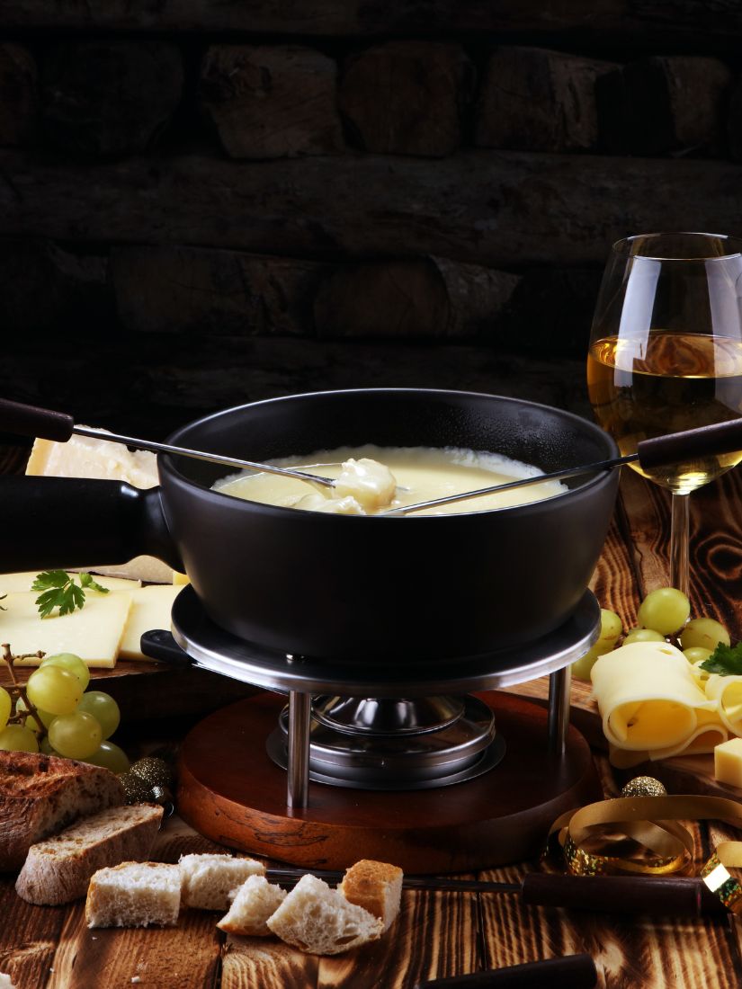 Käsefondue mit Zutaten auf einem gedeckten Tisch