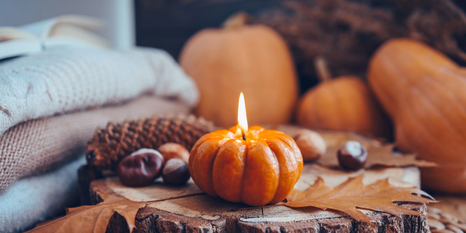 Kürbiskerze, eine gemütliche Decke und herbstliche Deko