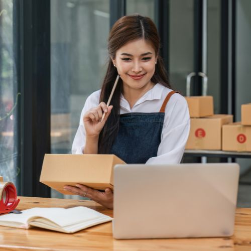 Junge Frau mit Paket und Laptop